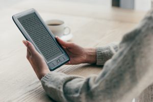 cropped view of woman studing with e-book near cup of coffee