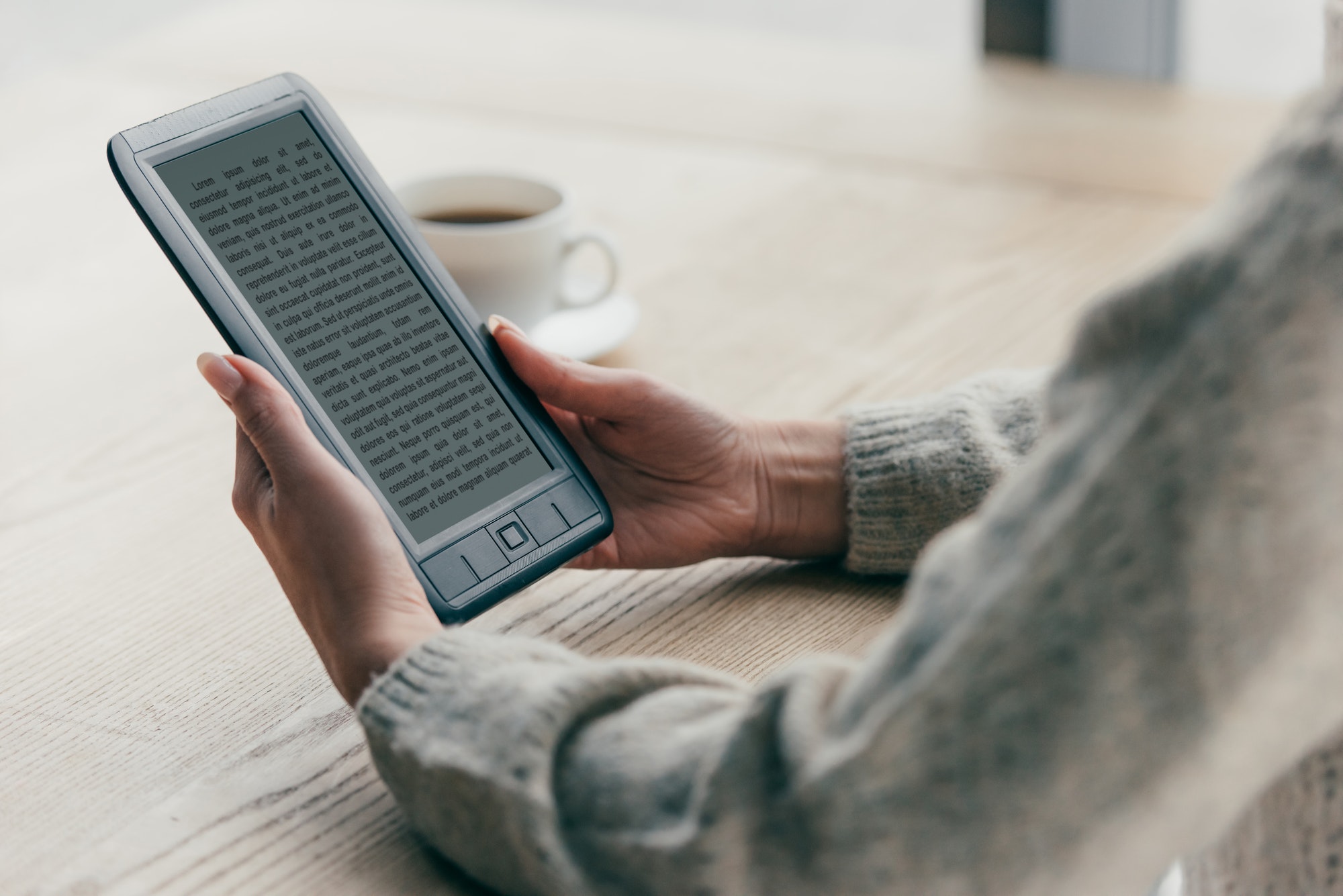 cropped view of woman studing with e-book near cup of coffee